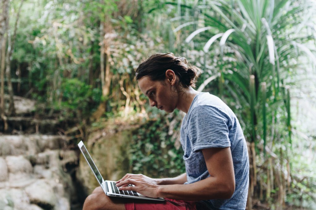 White man using computer laptop at waterfall